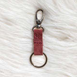 Red leather keychain with metal clasp on a white fur surface