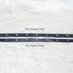 Two leather straps with metal rings on a white textured background