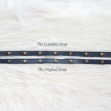Two leather straps with metal rings on a white textured background