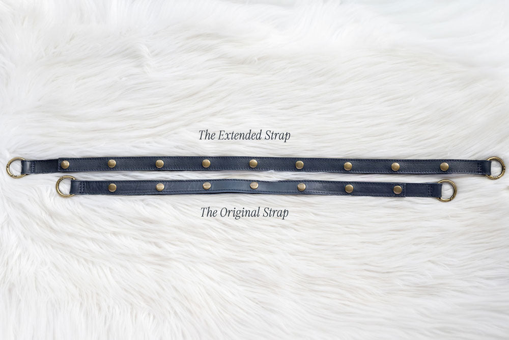 Two leather straps with metal rings on a white textured background