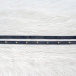 Navy leather straps with gold snaps on a white fur background