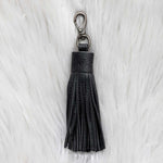 Black tassel keychain on a white fur background