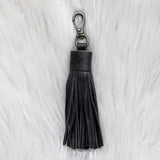 Black tassel keychain on a white fur background