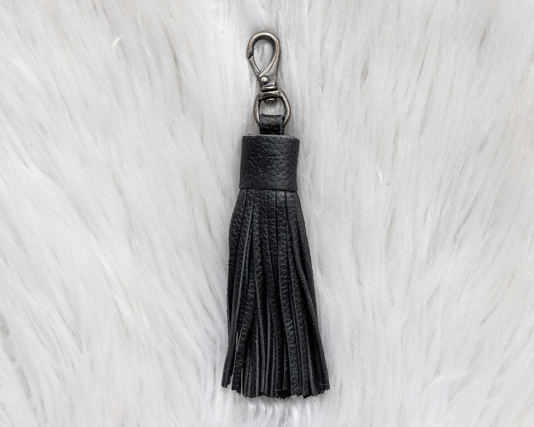 Black tassel keychain on a white fur background