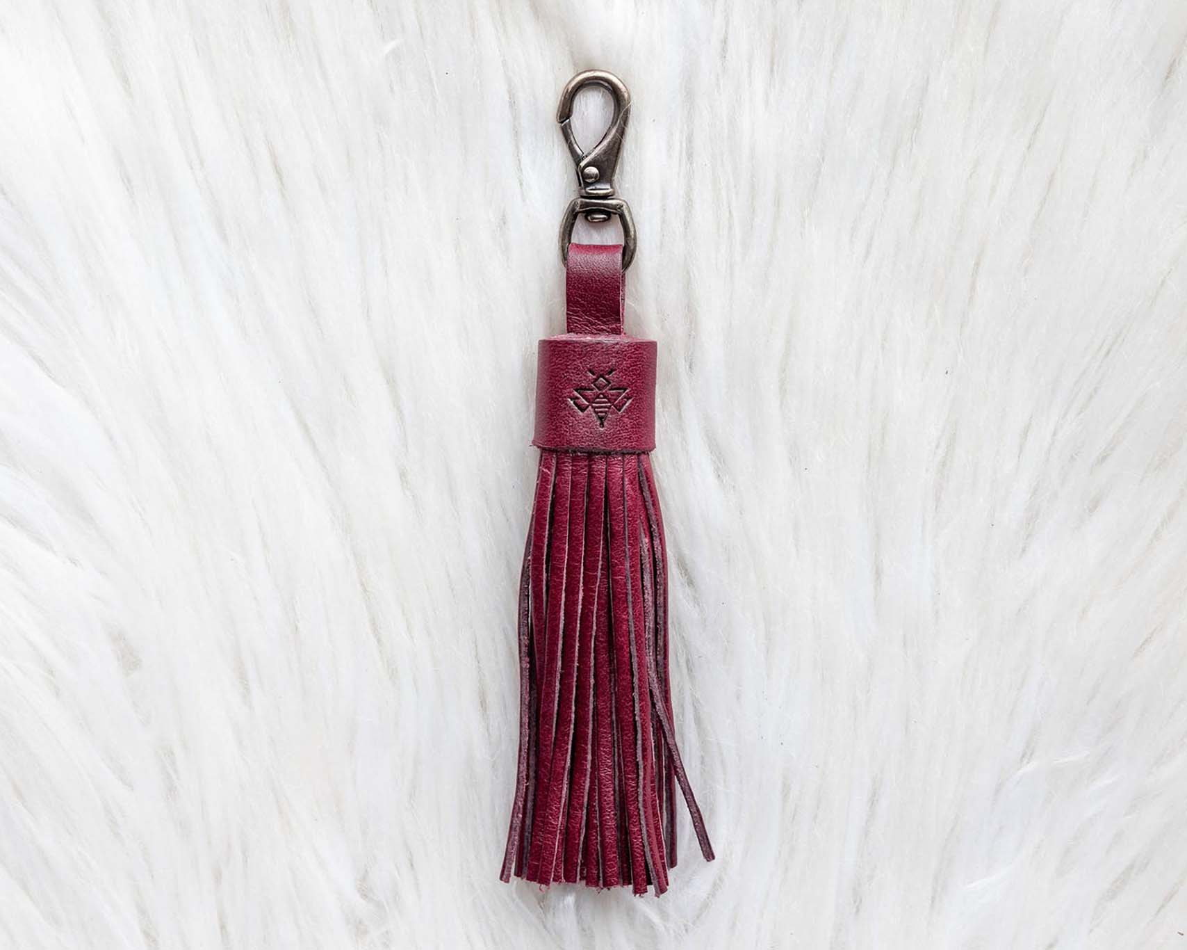 Maroon tassel keychain on a white textured background