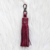 Maroon tassel keychain on a white textured background