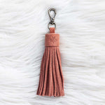 Pink tassel keychain on a textured white surface