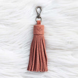 Pink tassel keychain on a textured white surface