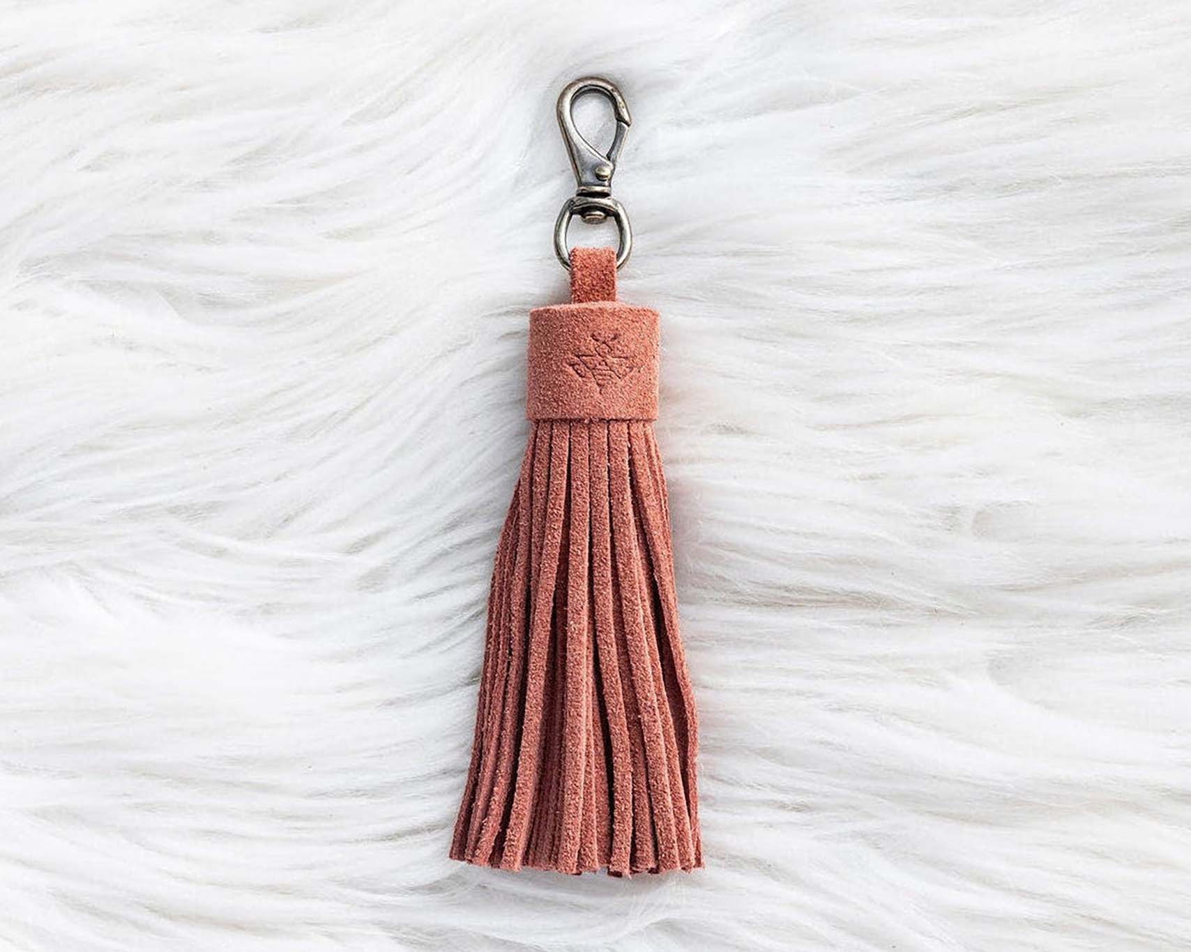 Pink tassel keychain on a textured white surface