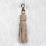 Beige tassel keychain on a white textured background