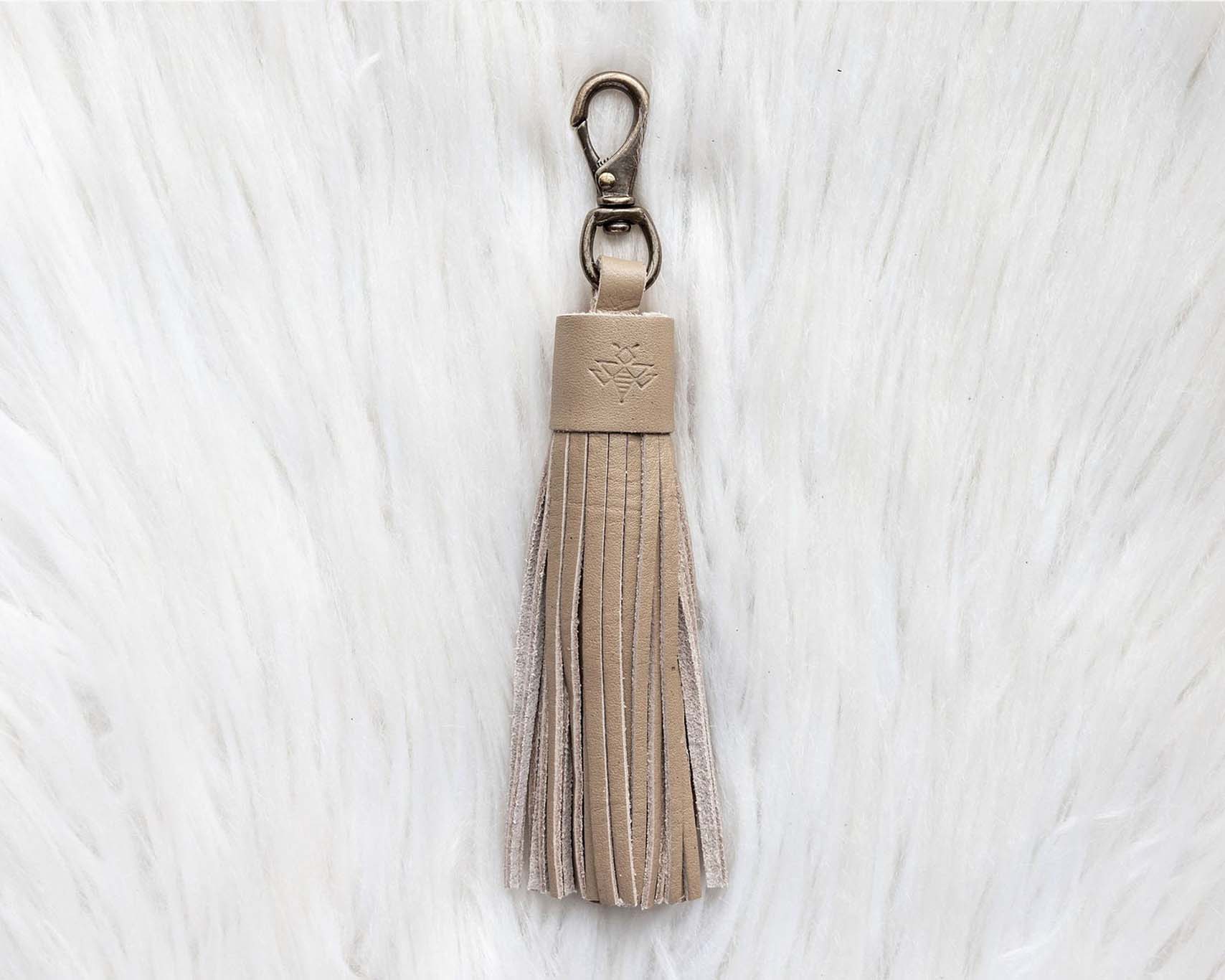 Beige tassel keychain on a white textured background