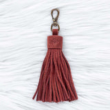 Red tassel keychain on a textured white background