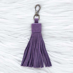 Purple tassel keychain on a textured white surface