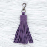 Purple tassel keychain on a textured white surface