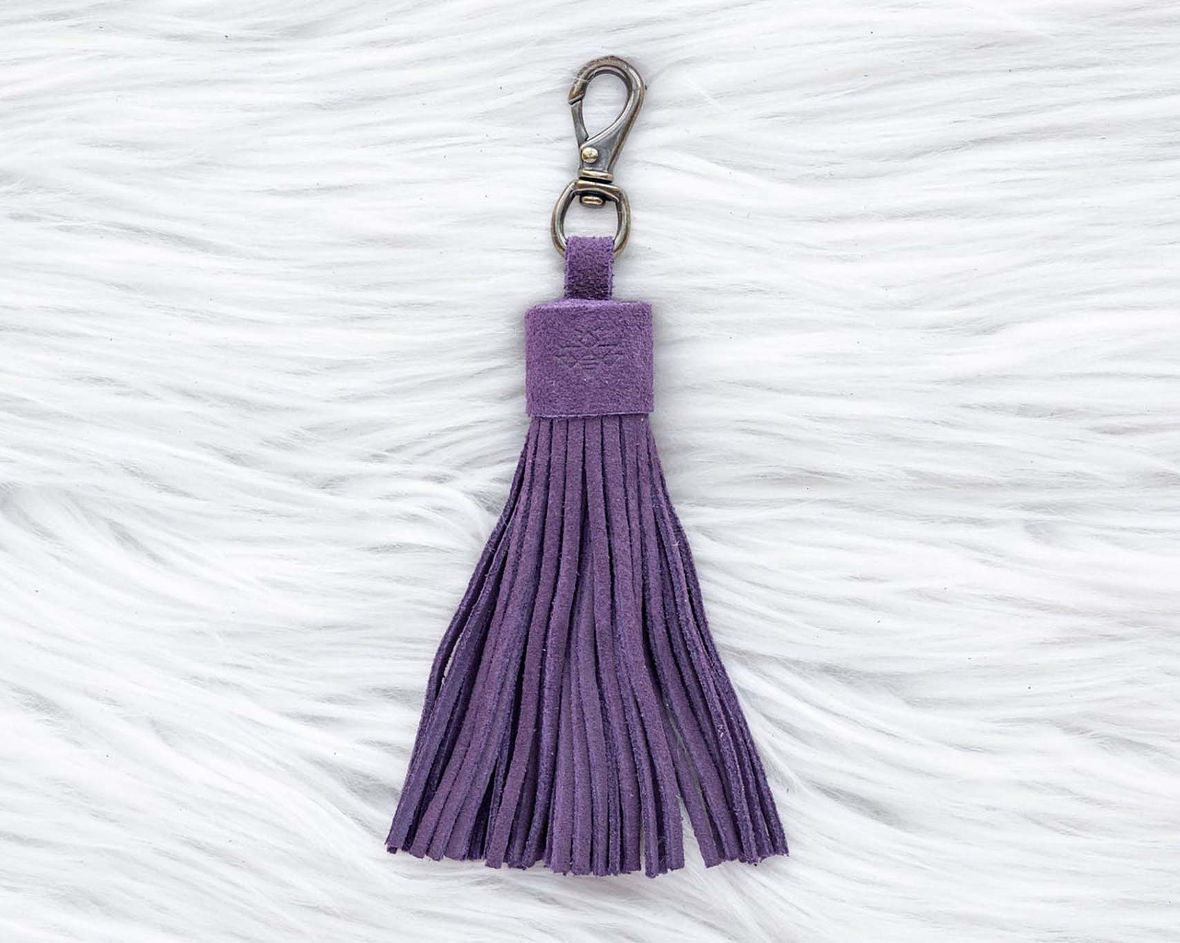 Purple tassel keychain on a textured white surface